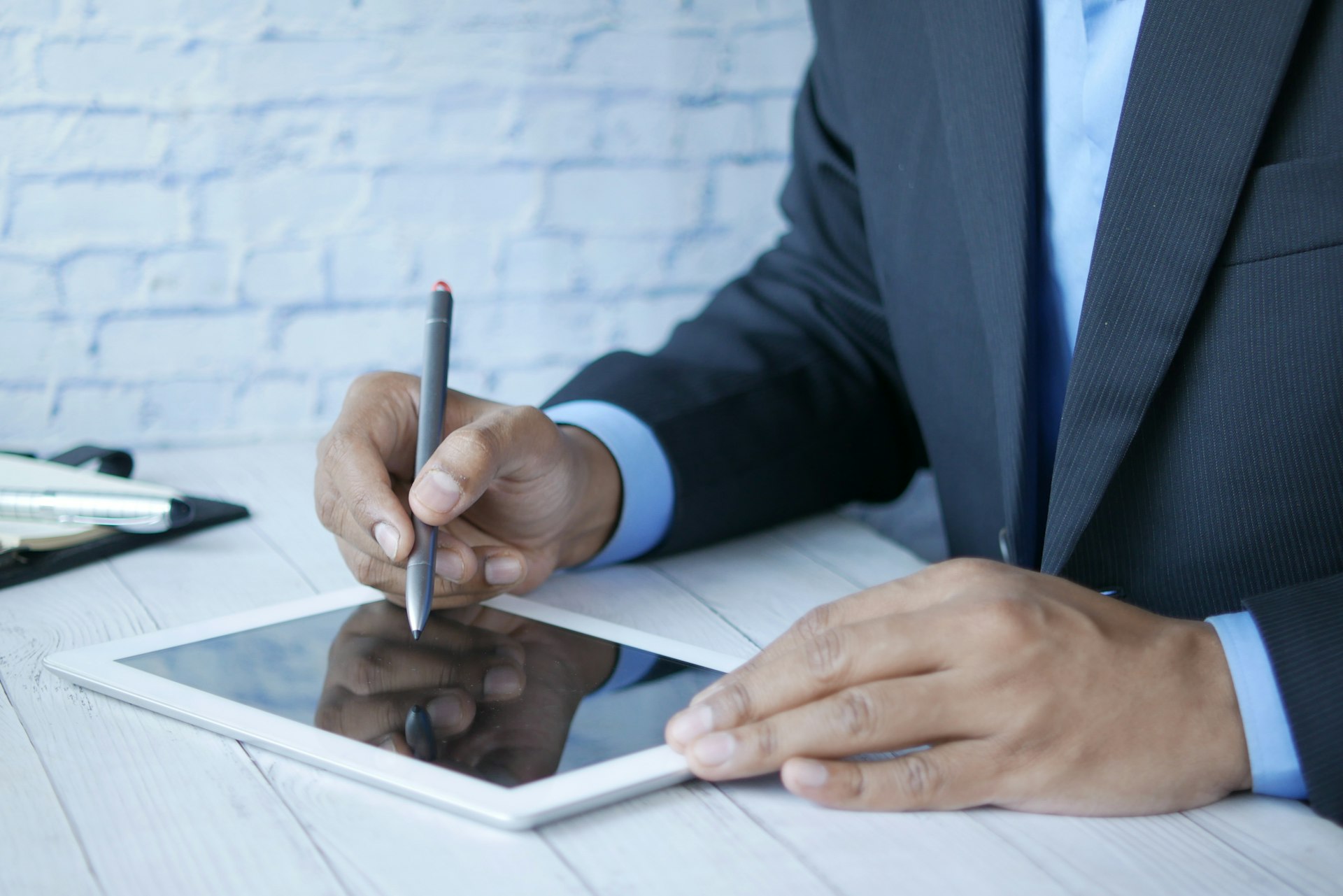 a man in a suit writing on a tablet